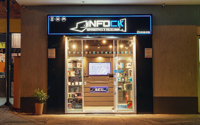 Vitrine iluminada da INFOCK vista da calçada, com letreiro em LED azul e placa de aberto
